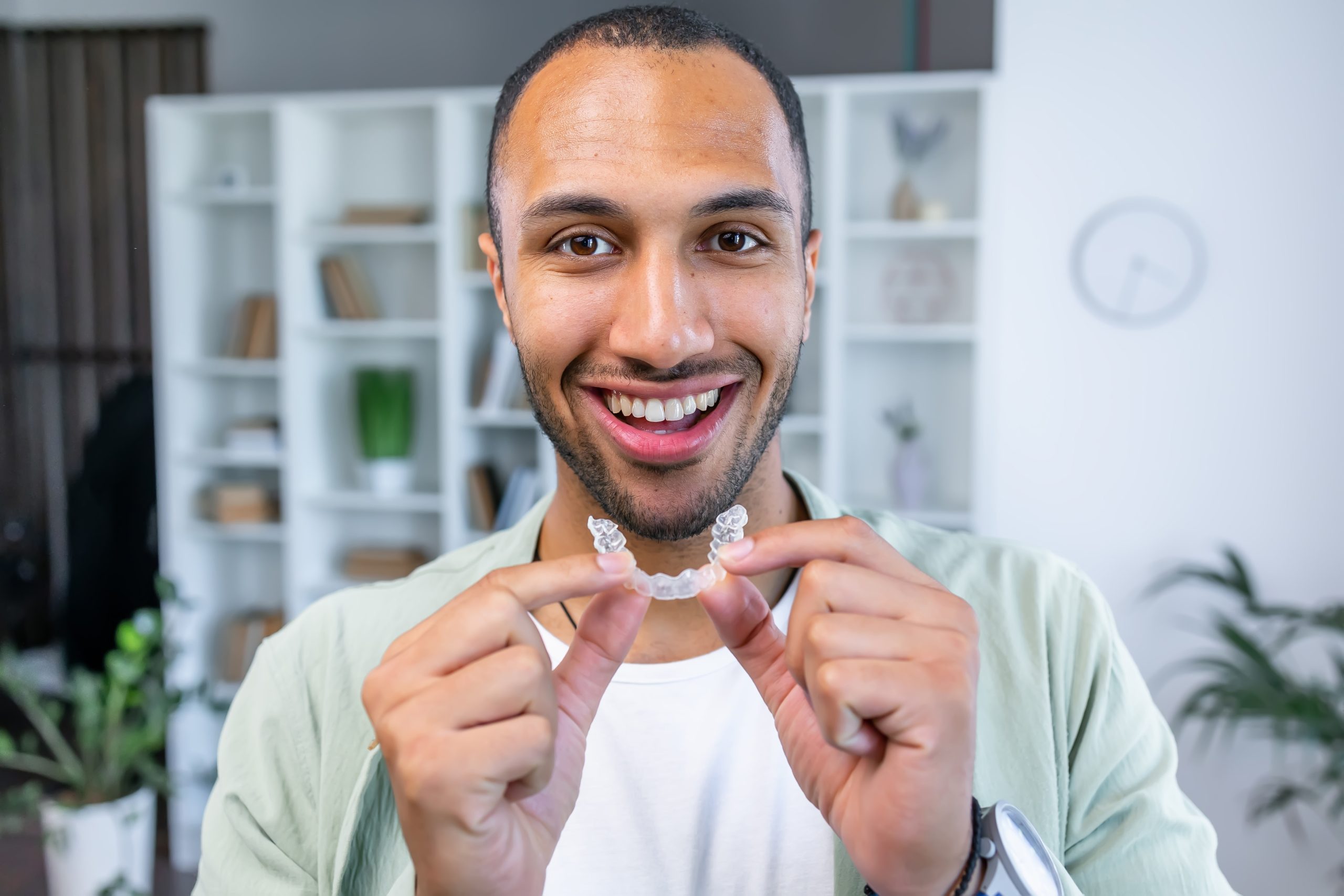 man smiling and putting in his clear aligner from the comfort of his own apartment