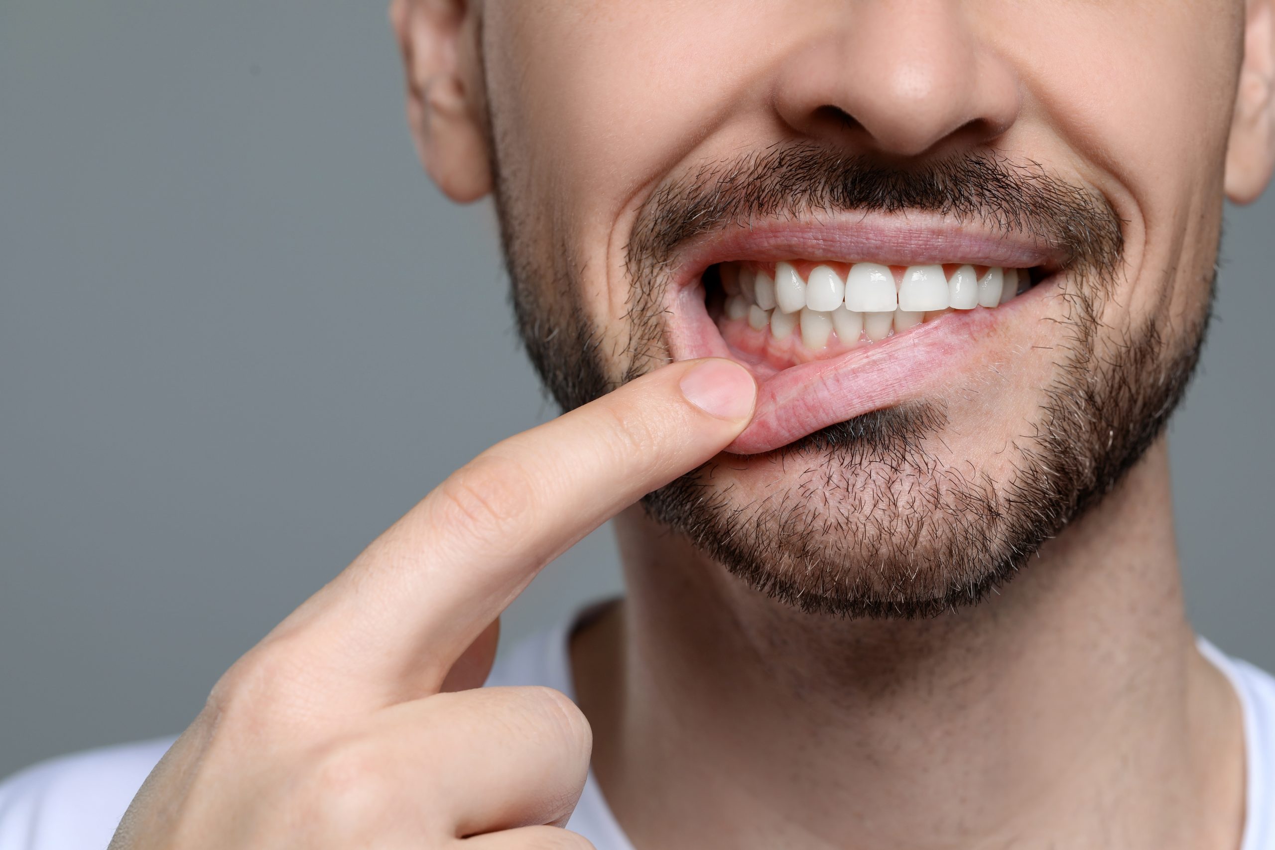 closeup of a man with healthy gums, grey background